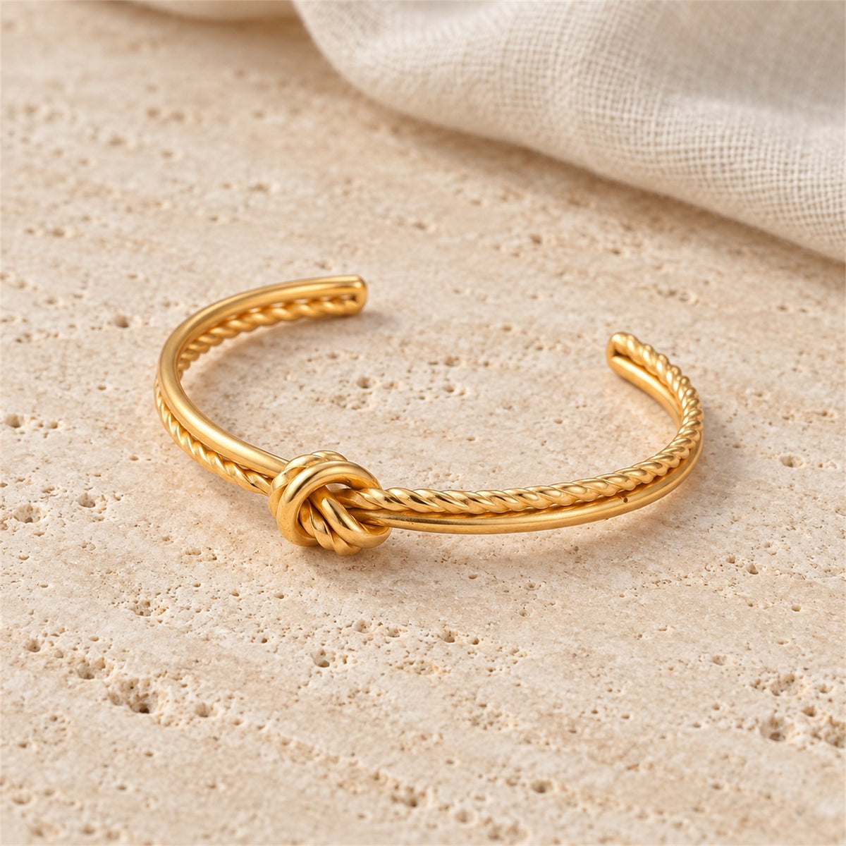 Amara Knot Cuff gold-tone knot style bracelet in a cream tone studio setting