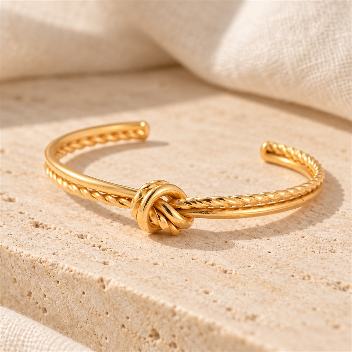 Amara Knot Cuff gold-tone knot style bracelet in a cream tone studio setting