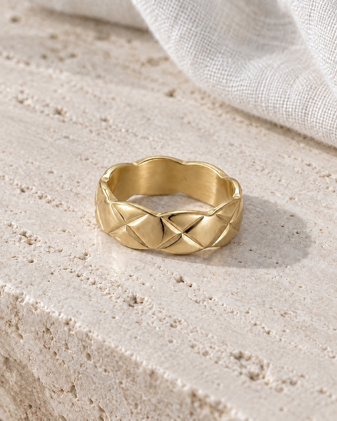 The Veria Twist Ring gold-tone band type ring on a cream studio background