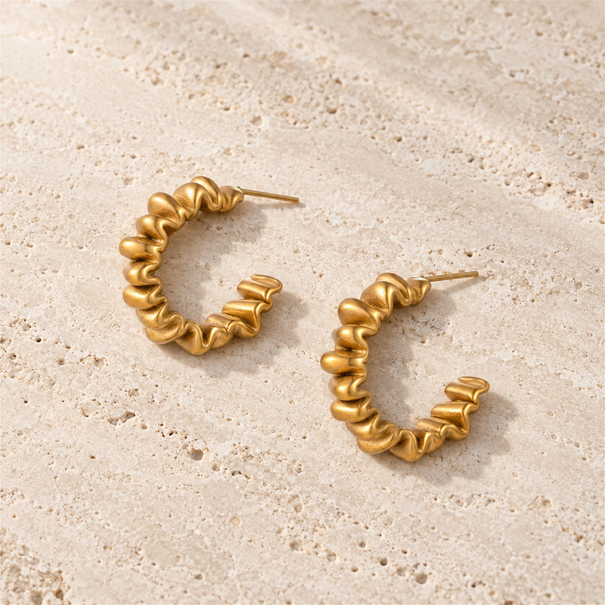 Vela Twist Hoops gold-tone earrings on a white background