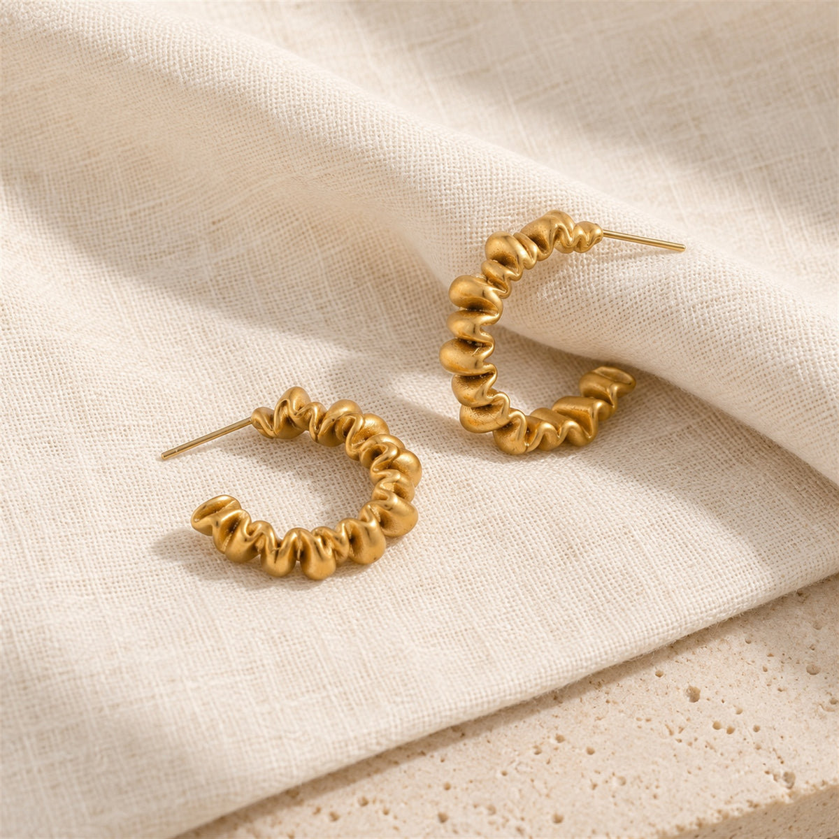 Vela Twist Hoops gold-tone earrings on a white background