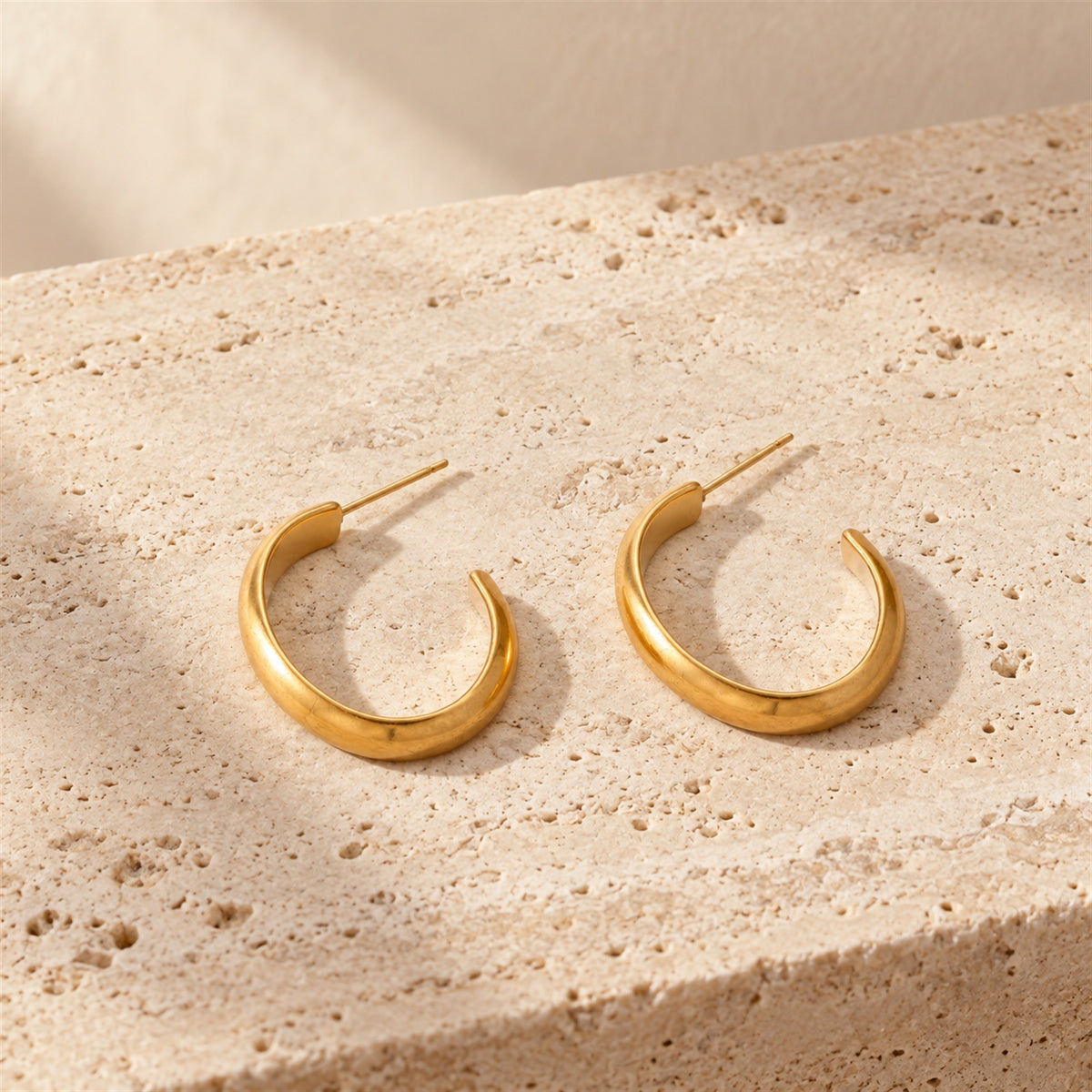 Veria Solea Hoops gold-tone earrings in a cream coloured studio setting